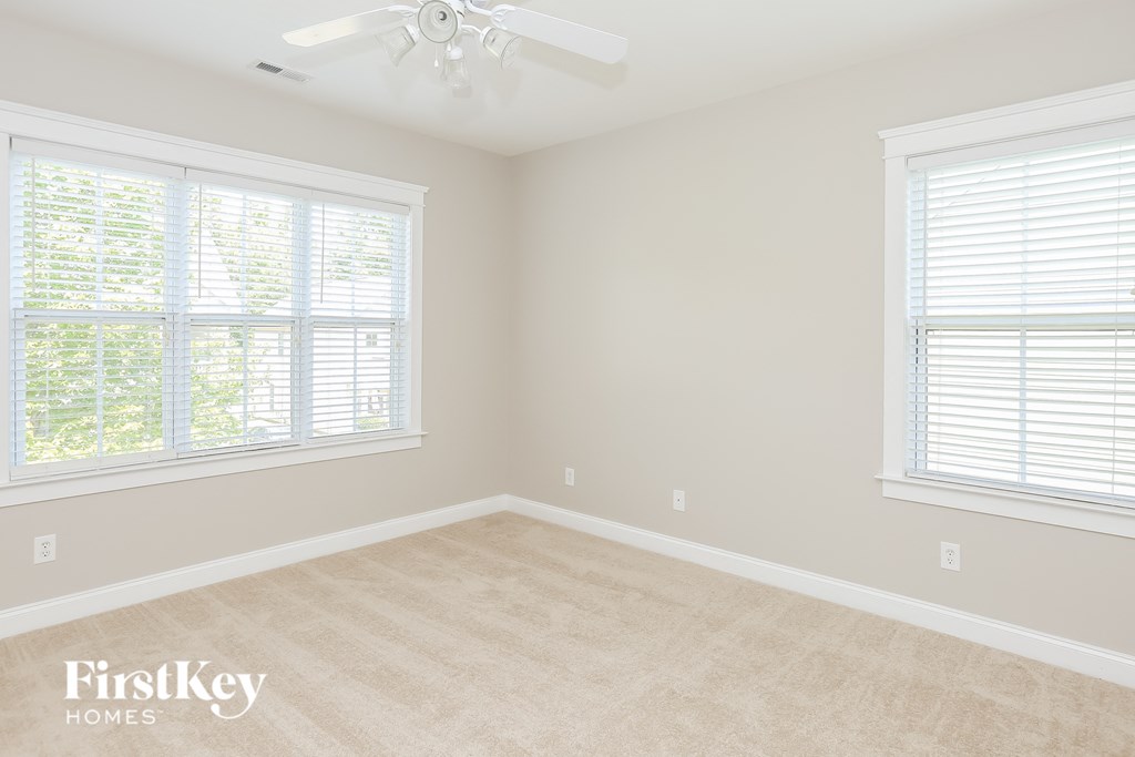 a empty room with two windows and a ceiling fan