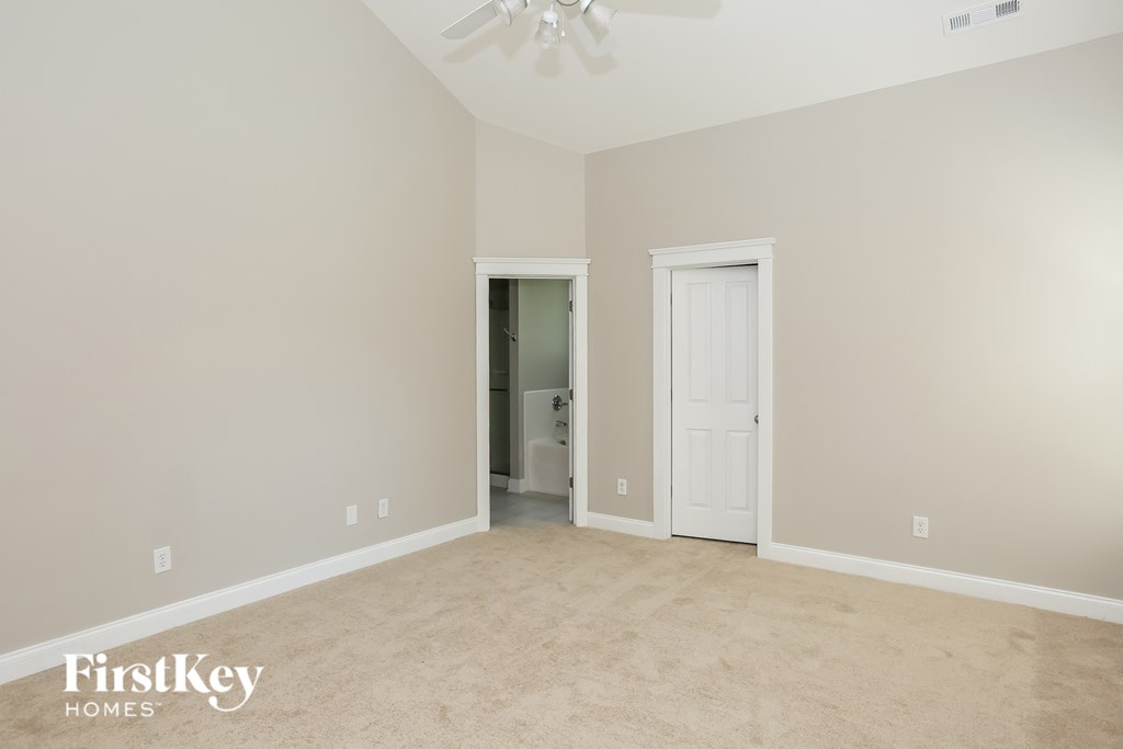 a bedroom with a carpeted floor and a door to a bathroom