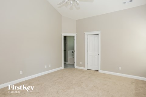 a bedroom with a carpeted floor and a door to a bathroom