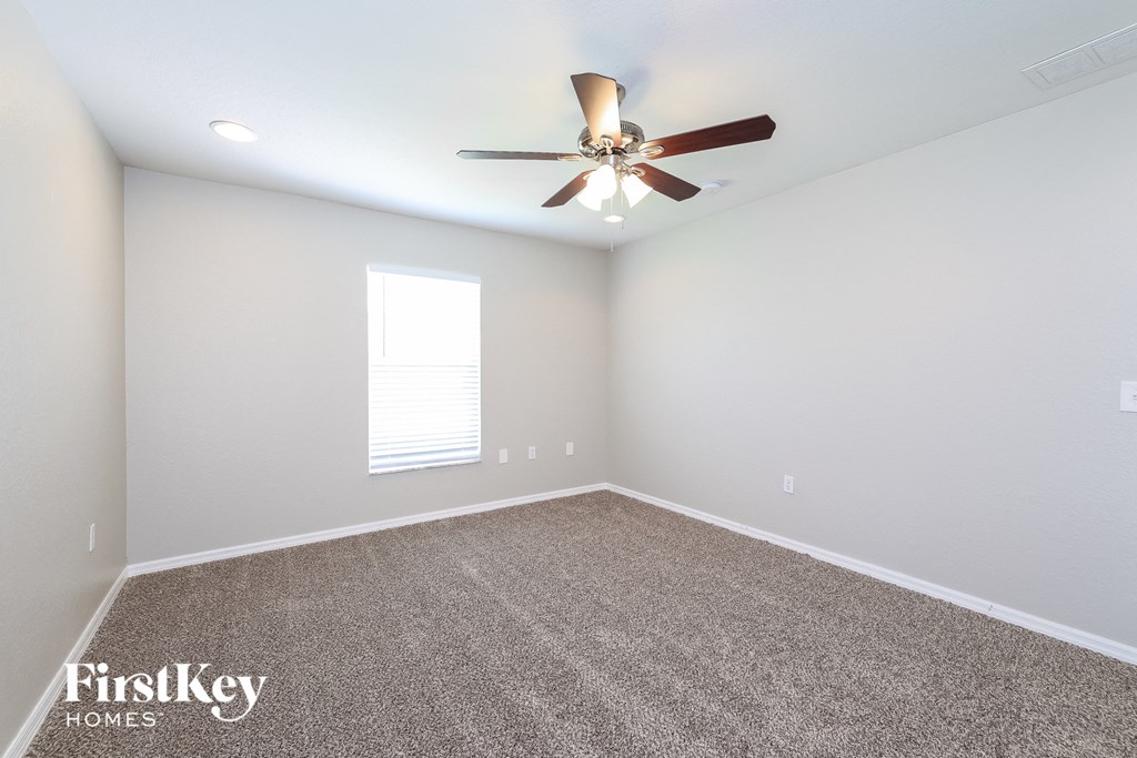 the bedroom has a carpeted floor and a ceiling fan