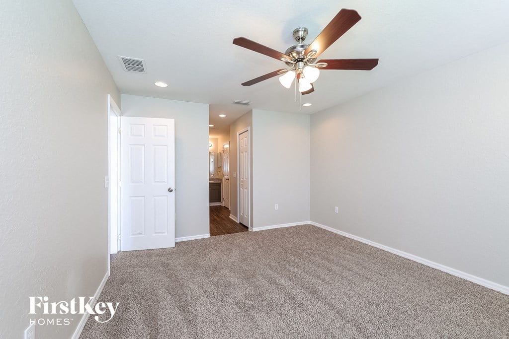a living room with a ceiling fan and a carpet