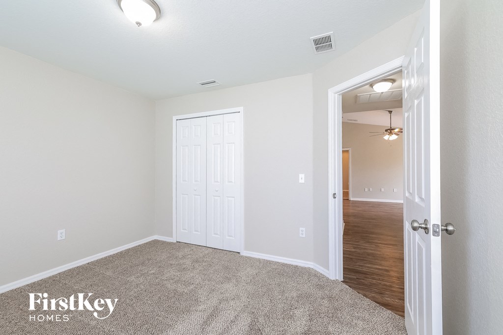 a bedroom with a door to a hallway and a carpeted floor