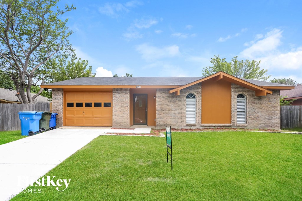 a small brick house with a lawn and a driveway