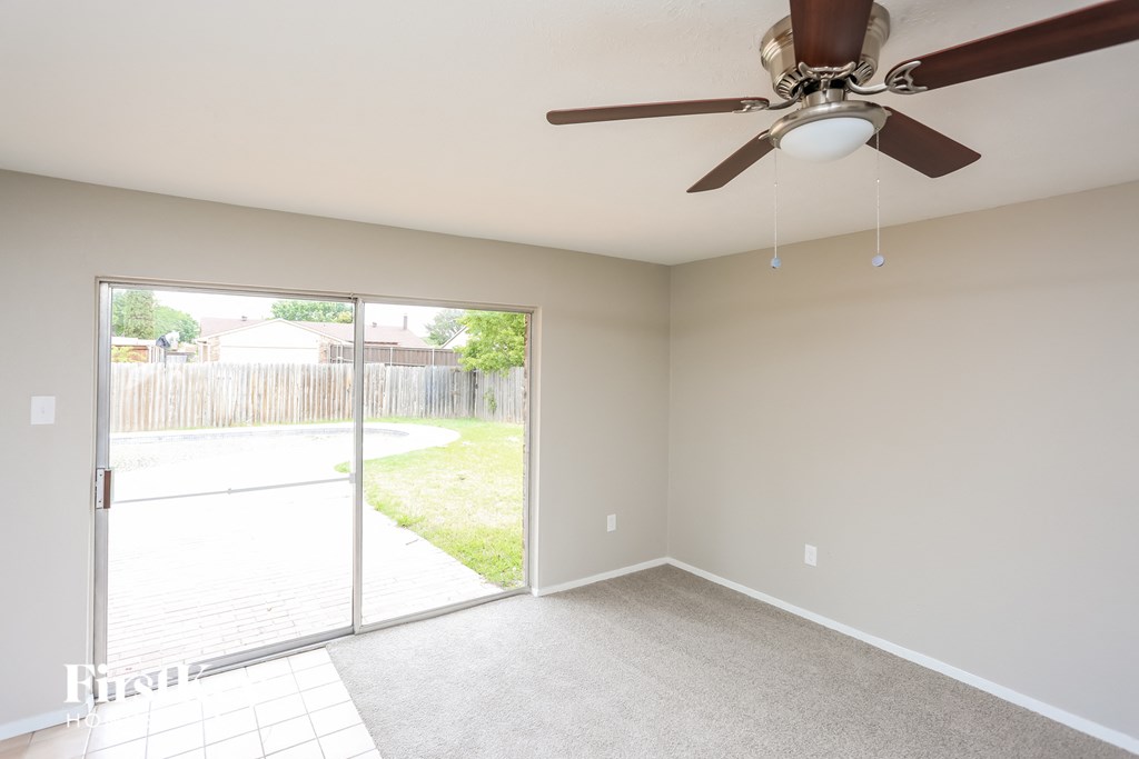 an empty living room with a ceiling fan and a sliding glass door