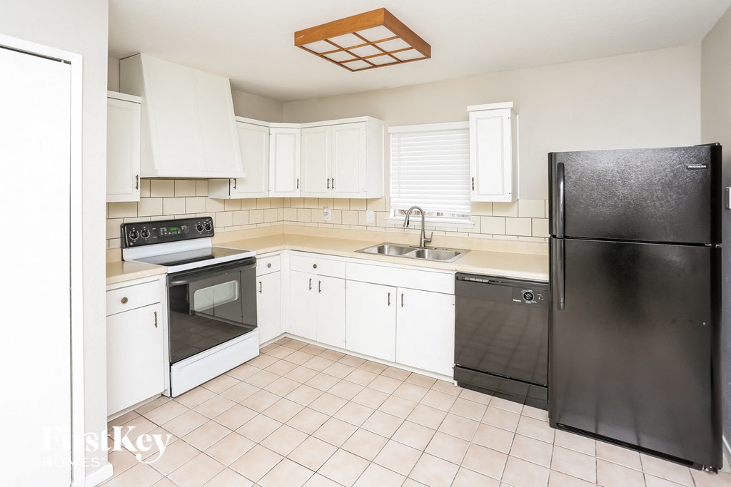 a kitchen with white cabinets and black appliances