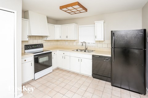 a kitchen with white cabinets and black appliances