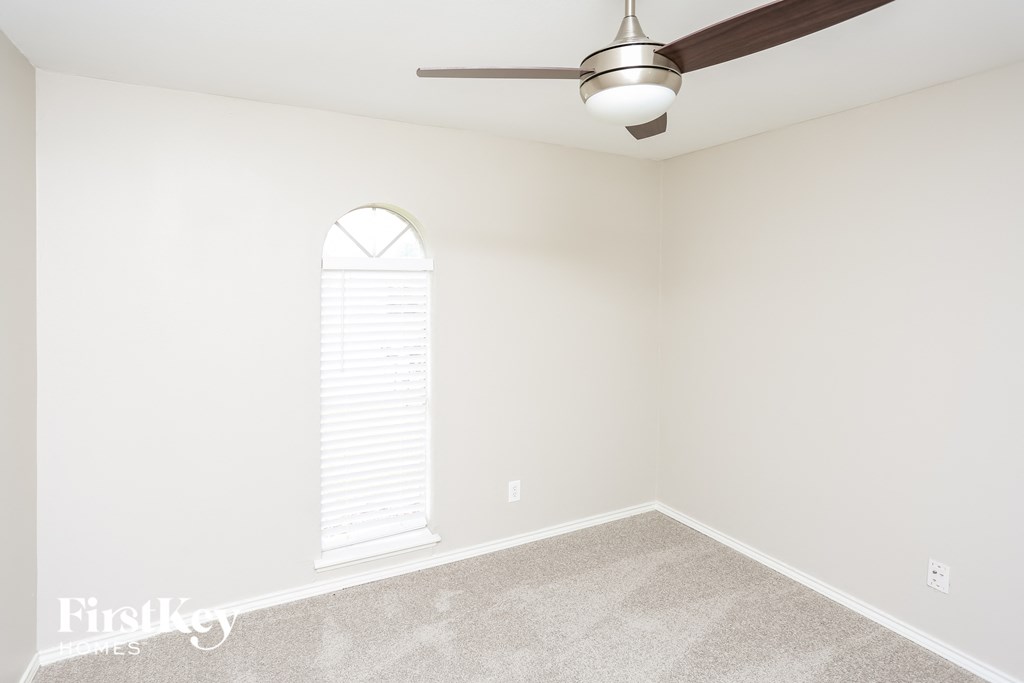 an empty room with a ceiling fan and a window