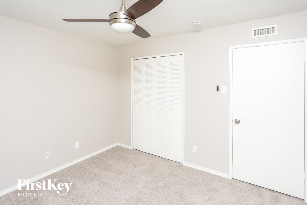 a bedroom with a ceiling fan and a closet