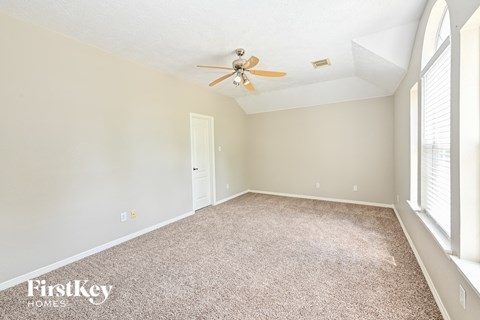 a spacious living room with carpet and a ceiling fan