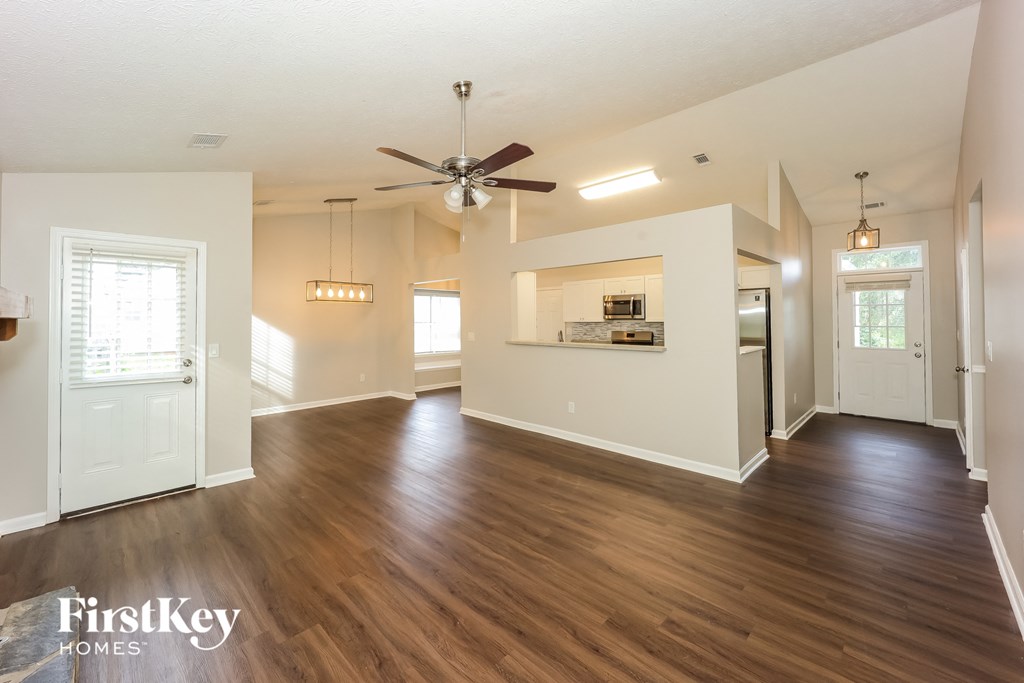 A spacious room with wooden floors and a ceiling fan.