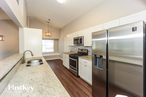 A kitchen with a stainless steel refrigerator and a marble countertop.