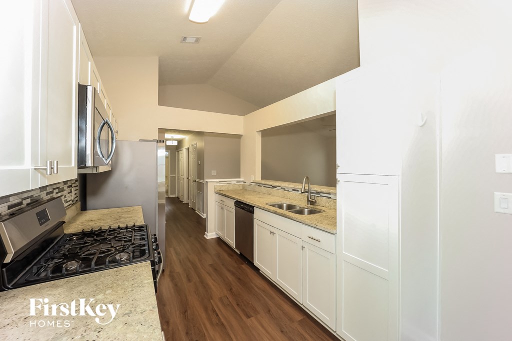 A kitchen with white cabinets and a marble countertop.