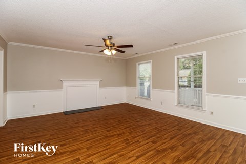 A spacious room with wooden floors and a ceiling fan.