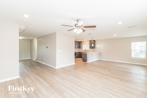 a living room and kitchen with wood flooring and a ceiling fan