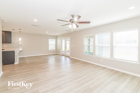 an empty living room with a ceiling fan and windows