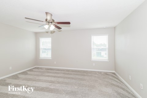 a spacious bedroom with carpet and a ceiling fan