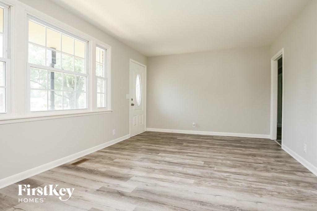 A room with wooden flooring and a door is shown.