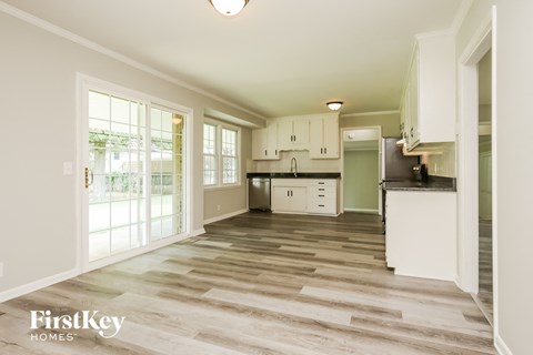 A kitchen with white cabinets and a wooden floor.