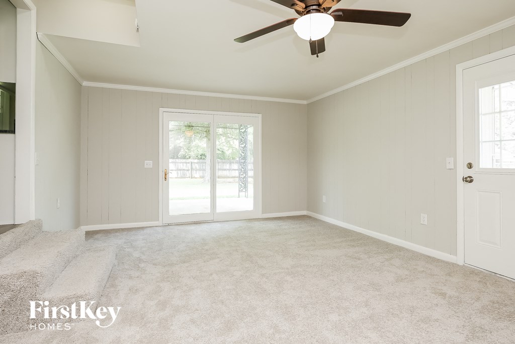 A spacious room with a ceiling fan and sliding glass doors.