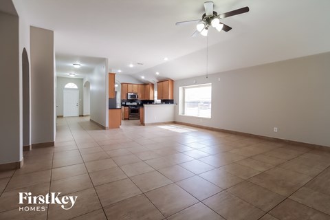 an empty living room with tile flooring and a ceiling fan