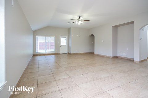 an empty living room with tiled floors and a ceiling fan