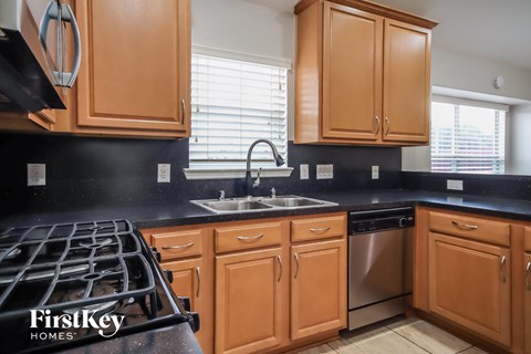 a kitchen with wooden cabinets and black countertops and a stove and sink