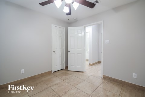 the master bedroom has a tile floor and a ceiling fan