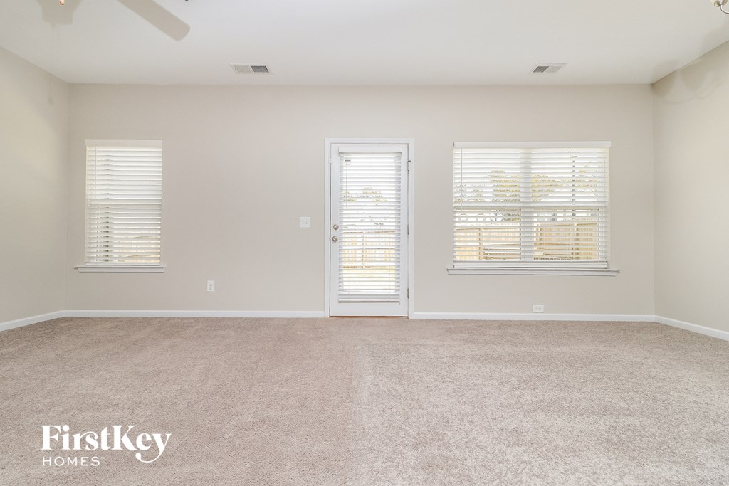 a room with a carpeted floor and two windows