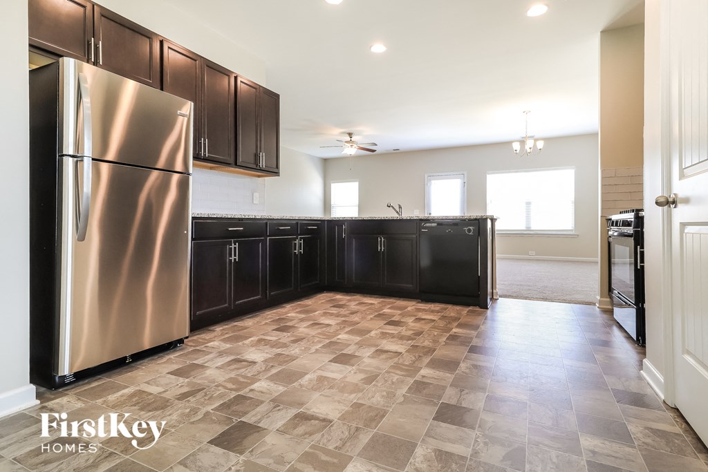 a kitchen with black cabinets and a stainless steel refrigerator