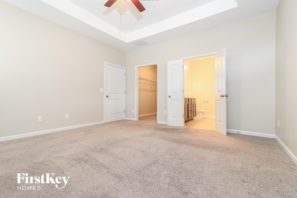 a spacious living room with carpet and a ceiling fan
