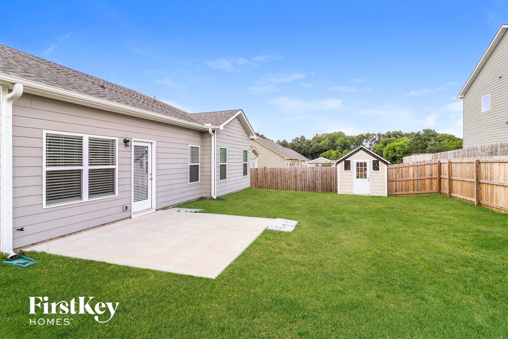 a backyard with a lawn and a fence and a house