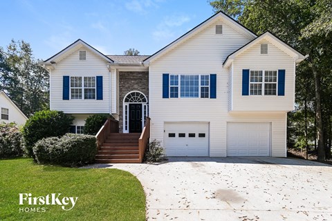 a white house with blue shutters and a white driveway