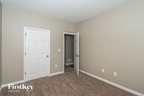 a bedroom with a white door and a carpeted floor