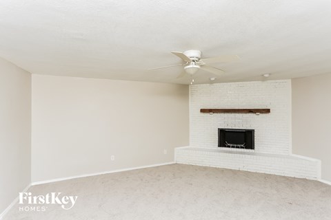 A living room with a fireplace and a fan on the ceiling.