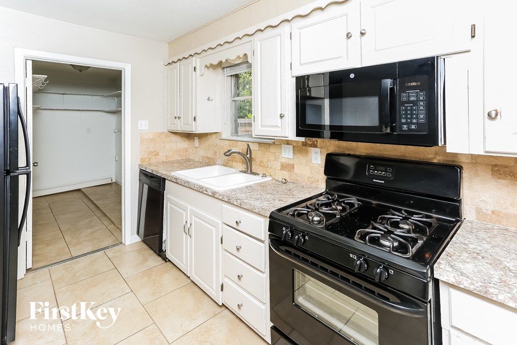 A kitchen with a black stove top oven and white cabinets.