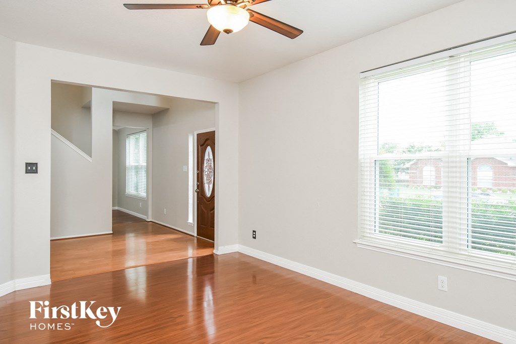 an empty living room with wood floors and a ceiling fan