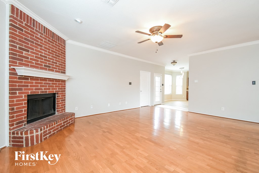a living room with a brick fireplace and a ceiling fan
