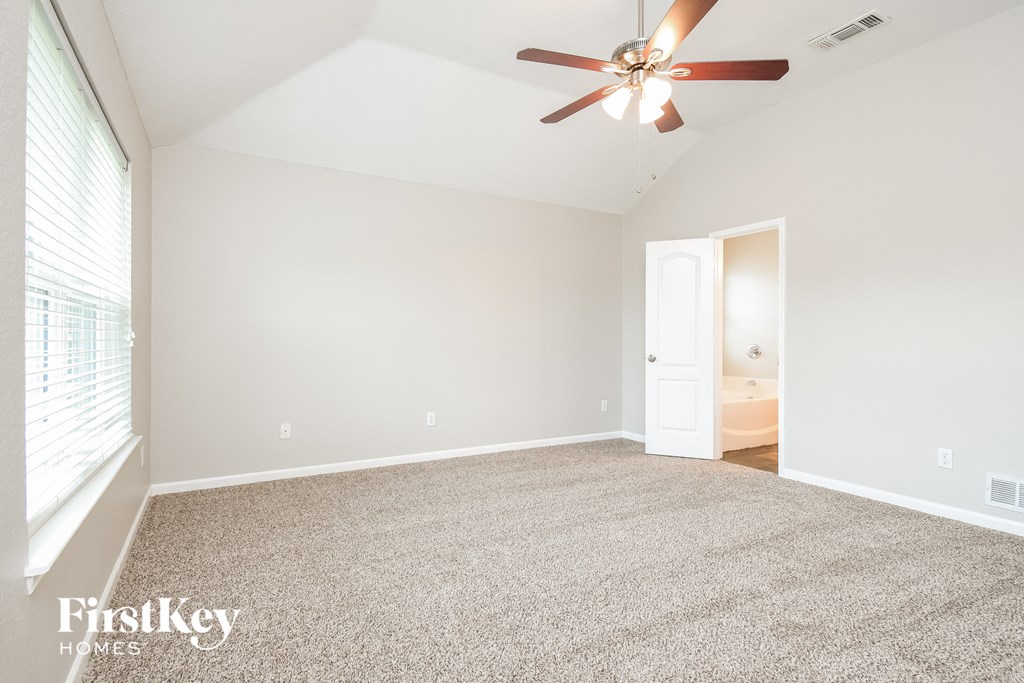 a spacious living room with carpet and a ceiling fan
