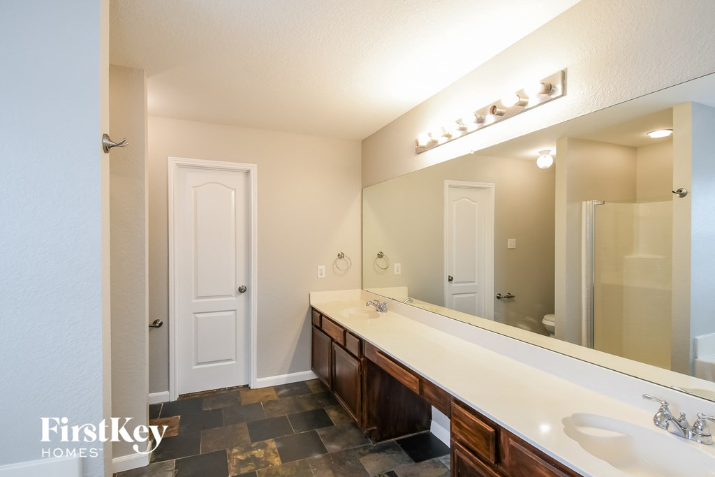 the master bathroom has a large vanity with a large mirror and a shower