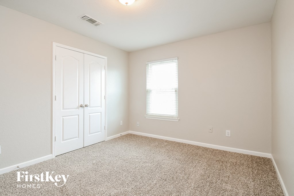 a bedroom with carpet and a white door and window