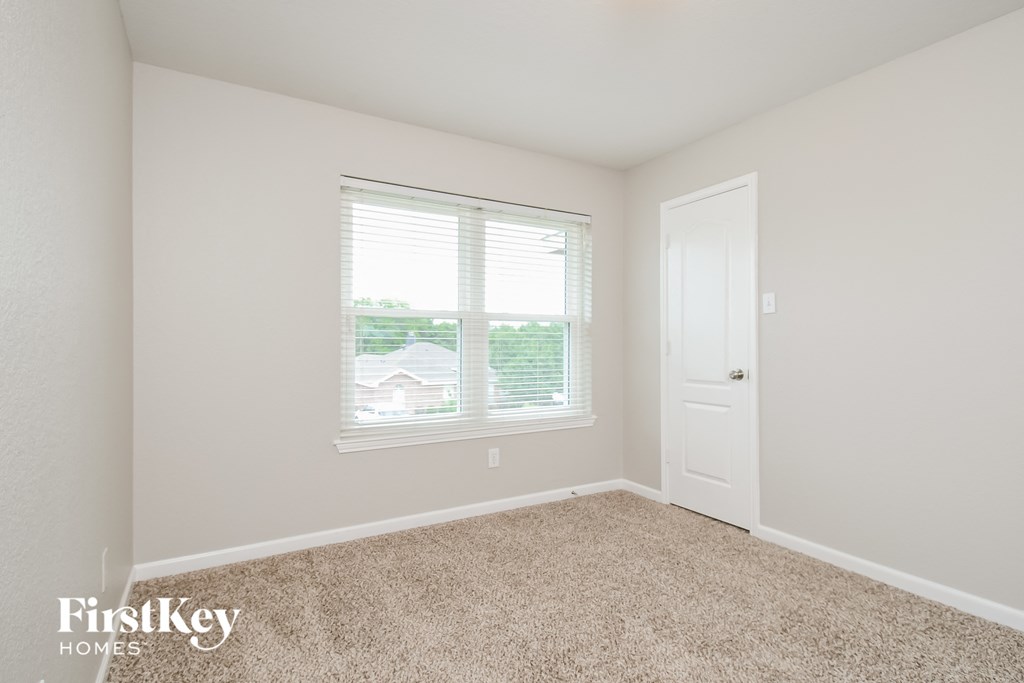 a bedroom with a window and a door and a carpeted floor