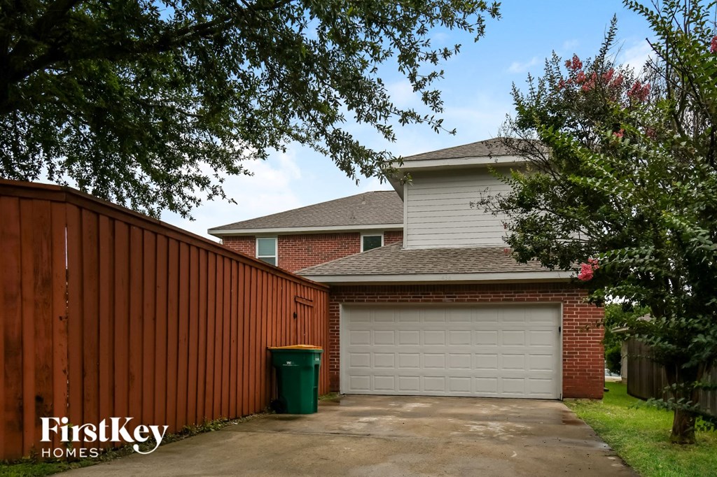 a garage door in front of a brick house with a wooden fence