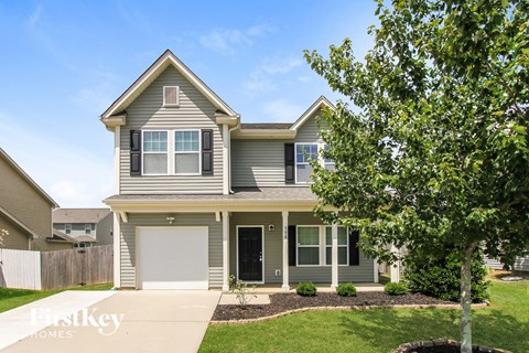 a gray house with a white garage door and a tree