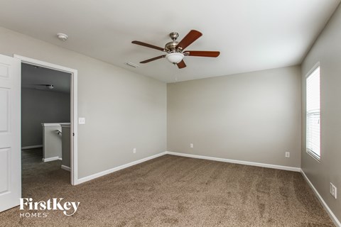 a bedroom with a ceiling fan and carpeting
