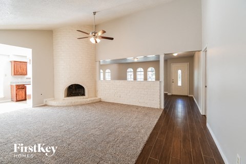 A spacious living room with a fireplace and a carpeted floor.