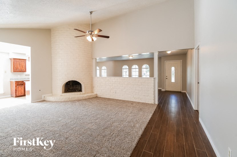 A spacious living room with a fireplace and a carpeted floor.