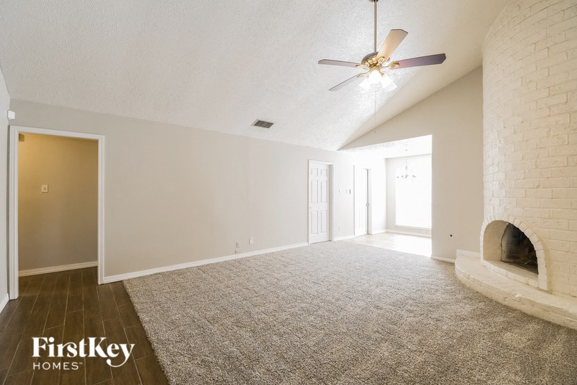 A spacious room with a ceiling fan and a fireplace.