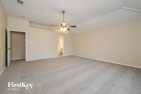 a spacious living room with carpet and a ceiling fan