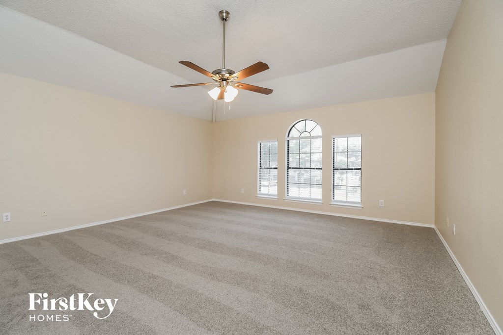 an empty living room with a ceiling fan and a window