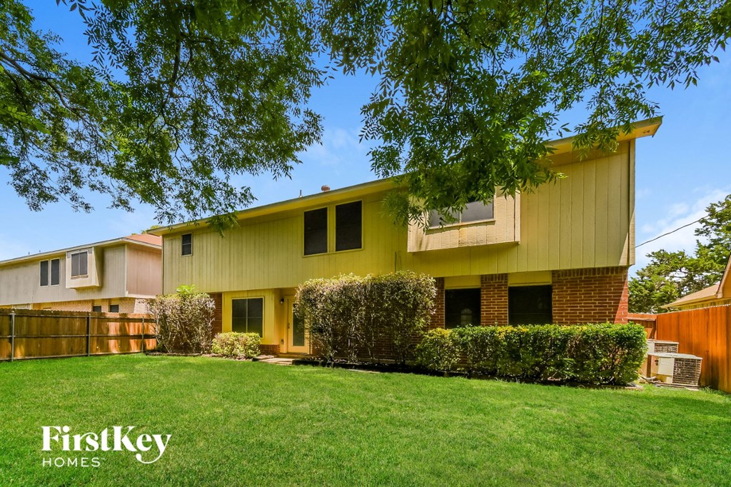 a yellow house with a lawn and a wooden fence